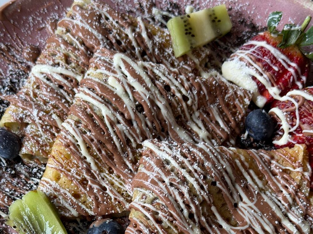 Quatre crêpes pliées en triangle, nappées de chocolat et saupoudrées de sucre